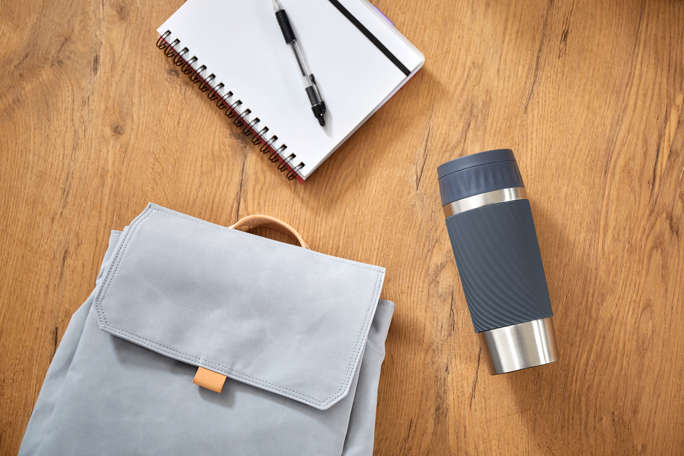 Bureau-opstelling: rugzak, notitieboek, pen en thermosbeker.