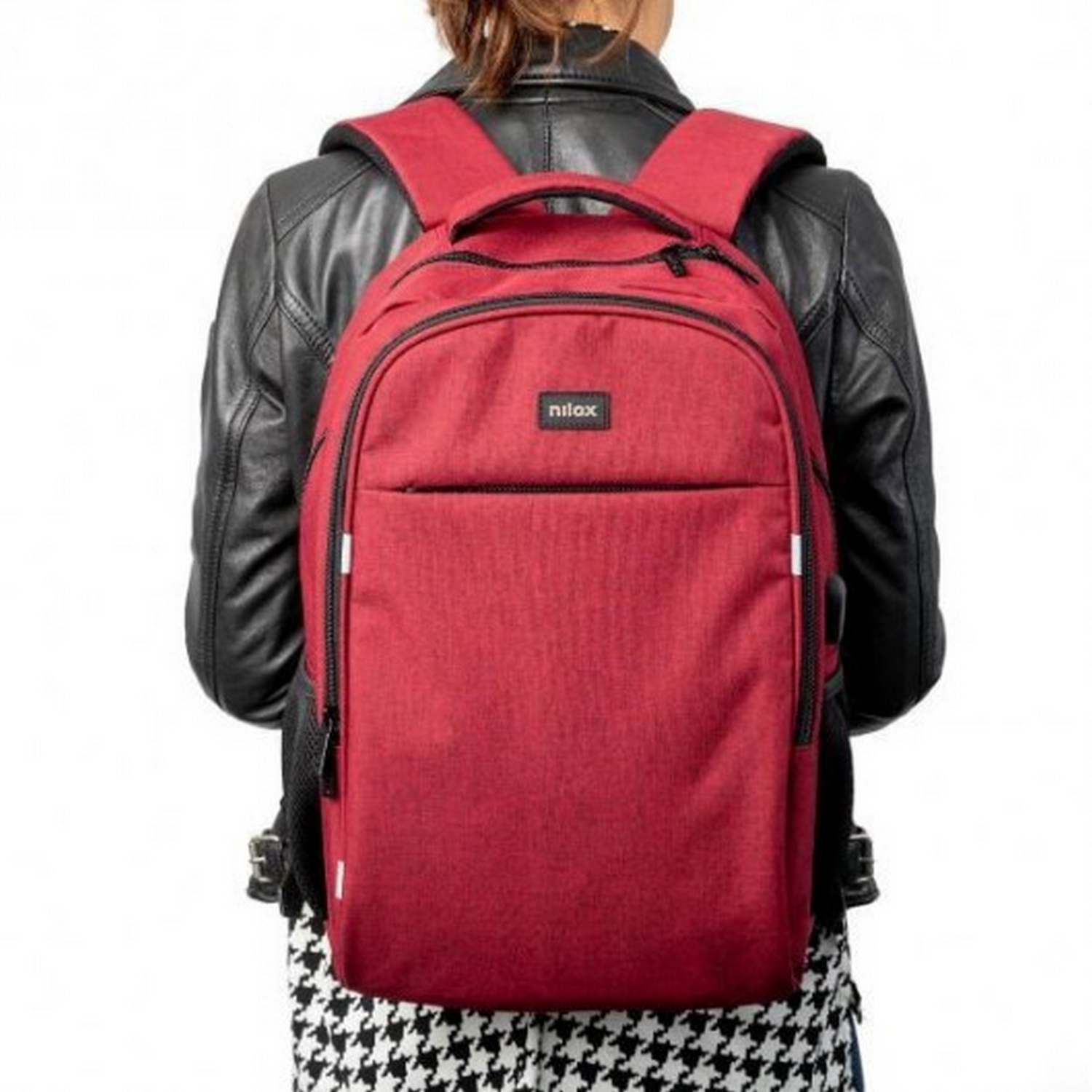 Una persona con chaqueta negra y mochila roja con 'nilox'. La persona está frente a un fondo blanco.