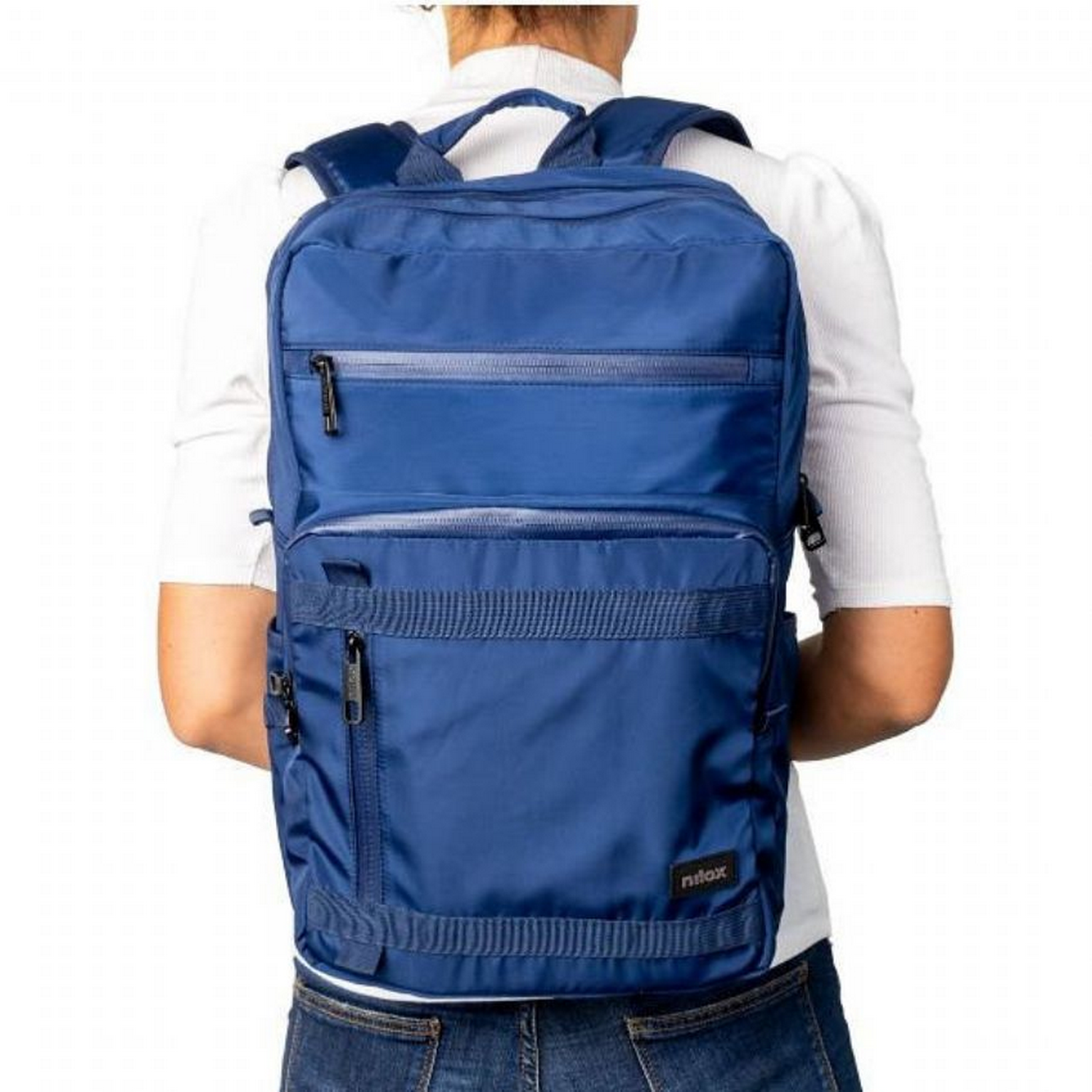 Mochila azul en la espalda de una persona. La persona usa camisa blanca y jeans azules.