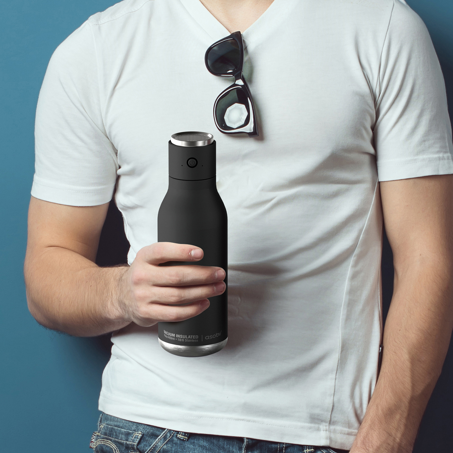 A person holding a black, insulated water bottle, with sunglasses on top.