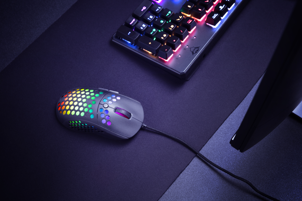 Siyah mouse, siyah mousepad üzerinde gökkuşağı ışıklarıyla. Arka planda klavye.