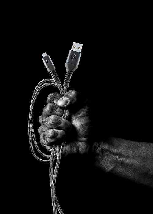 Un poing tenant deux câbles USB. Le fond est noir. Les câbles sont gris.
