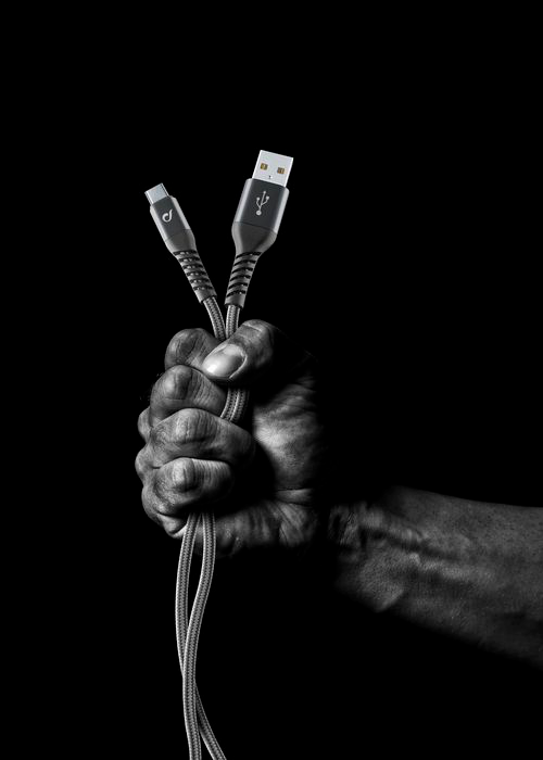 Mano che tiene due cavi USB. Uno è USB-C, l'altro è USB-A. Sfondo nero.