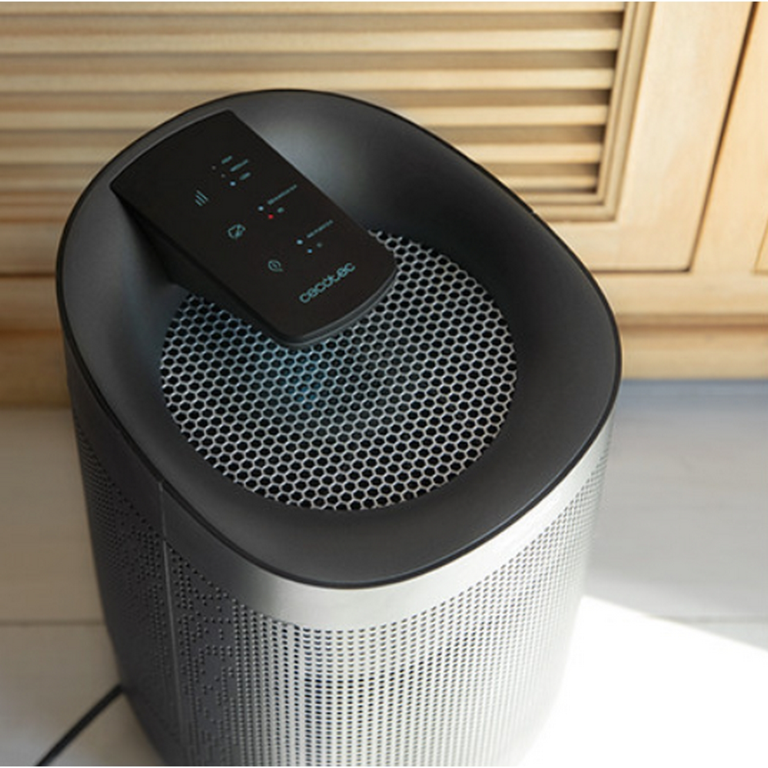 Purificador de aire negro y plateado con panel de control, sobre fondo de madera.