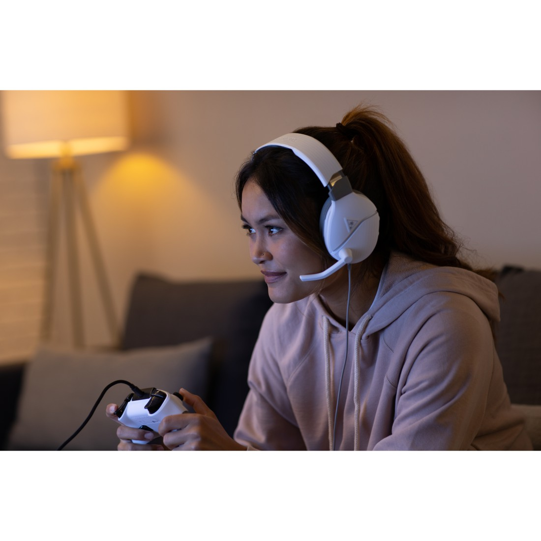 Eine Frau mit einem weißen Gaming-Headset, die ein Videospiel spielt. Sie hält ein Gamepad.