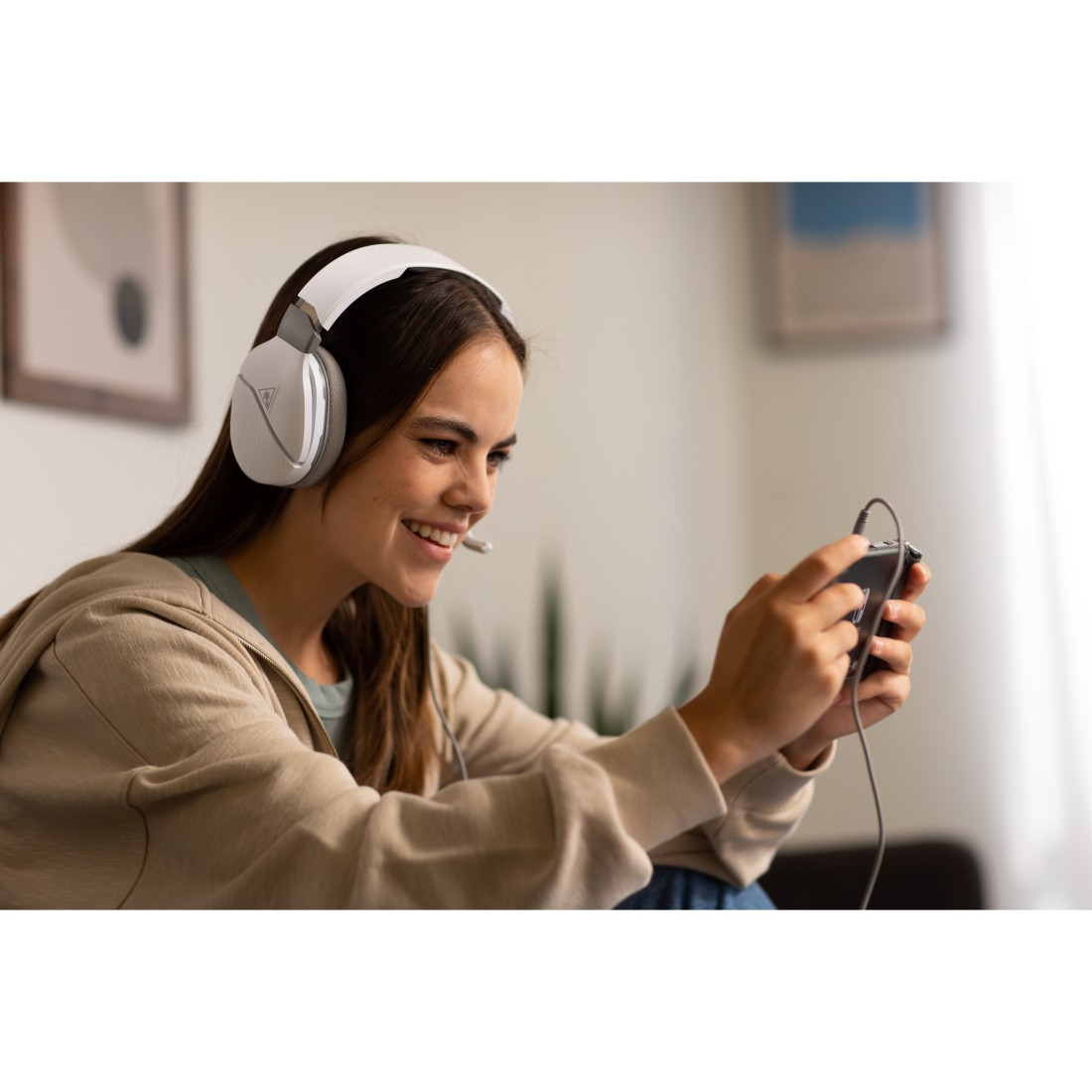 Eine Frau mit Headset lächelt, während sie ein Telefon hält und spielt.