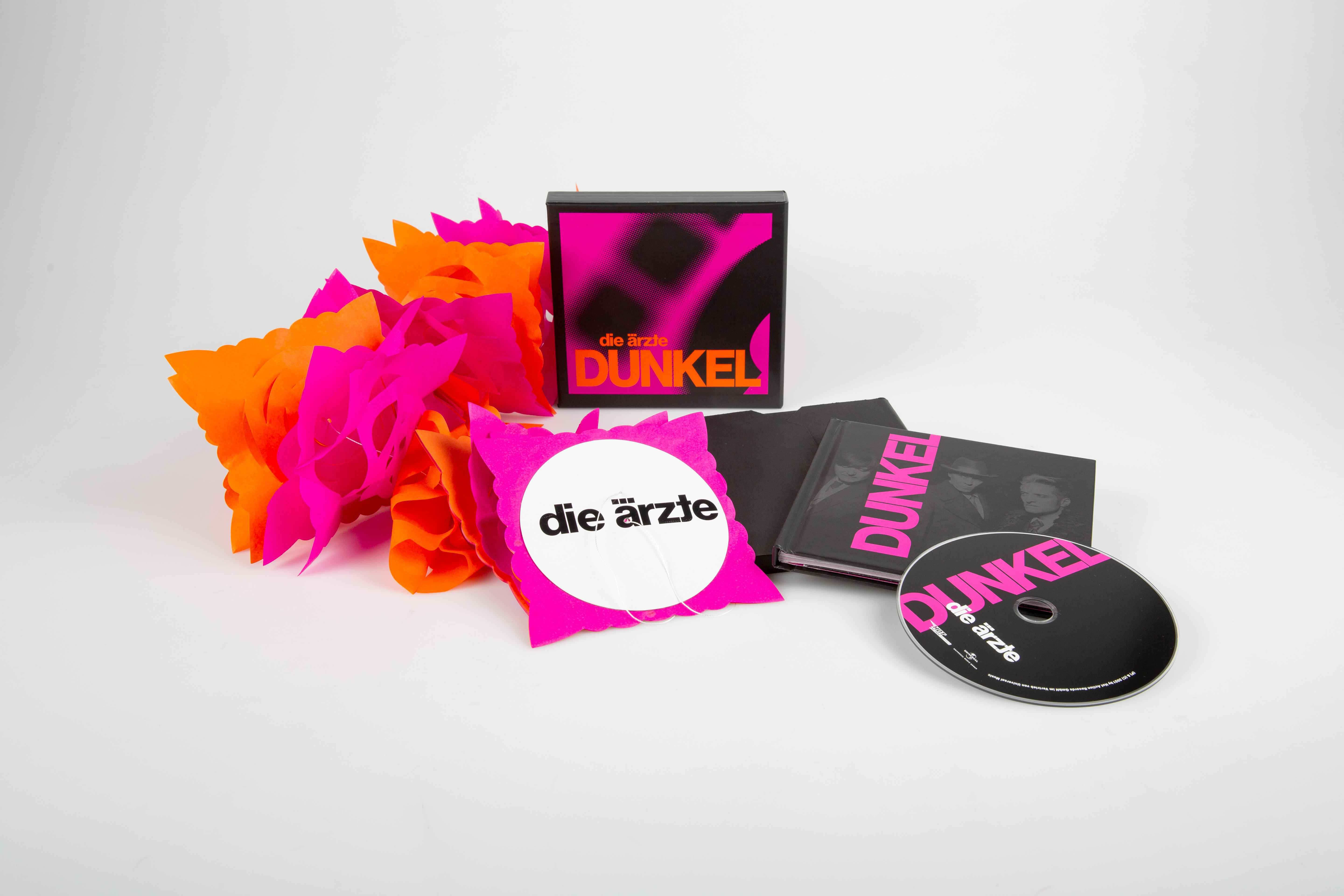 Eine Sammlung von Musikalben und verwandten Artikeln. Es gibt eine rosa-orange Papierdekoration.