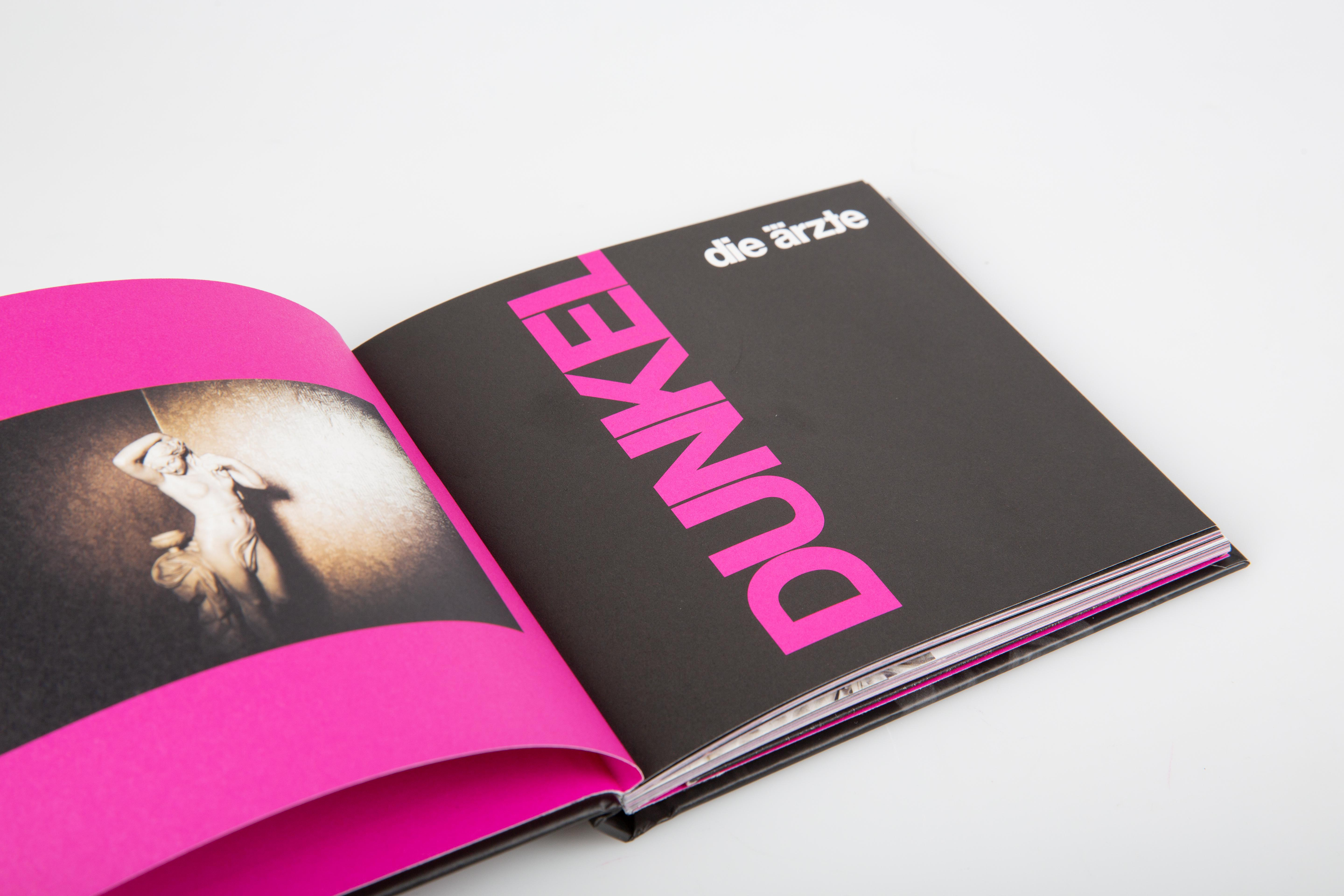 Ein offenes Buch mit dem Wort DUNKEL in Pink und einem Bild einer Person.