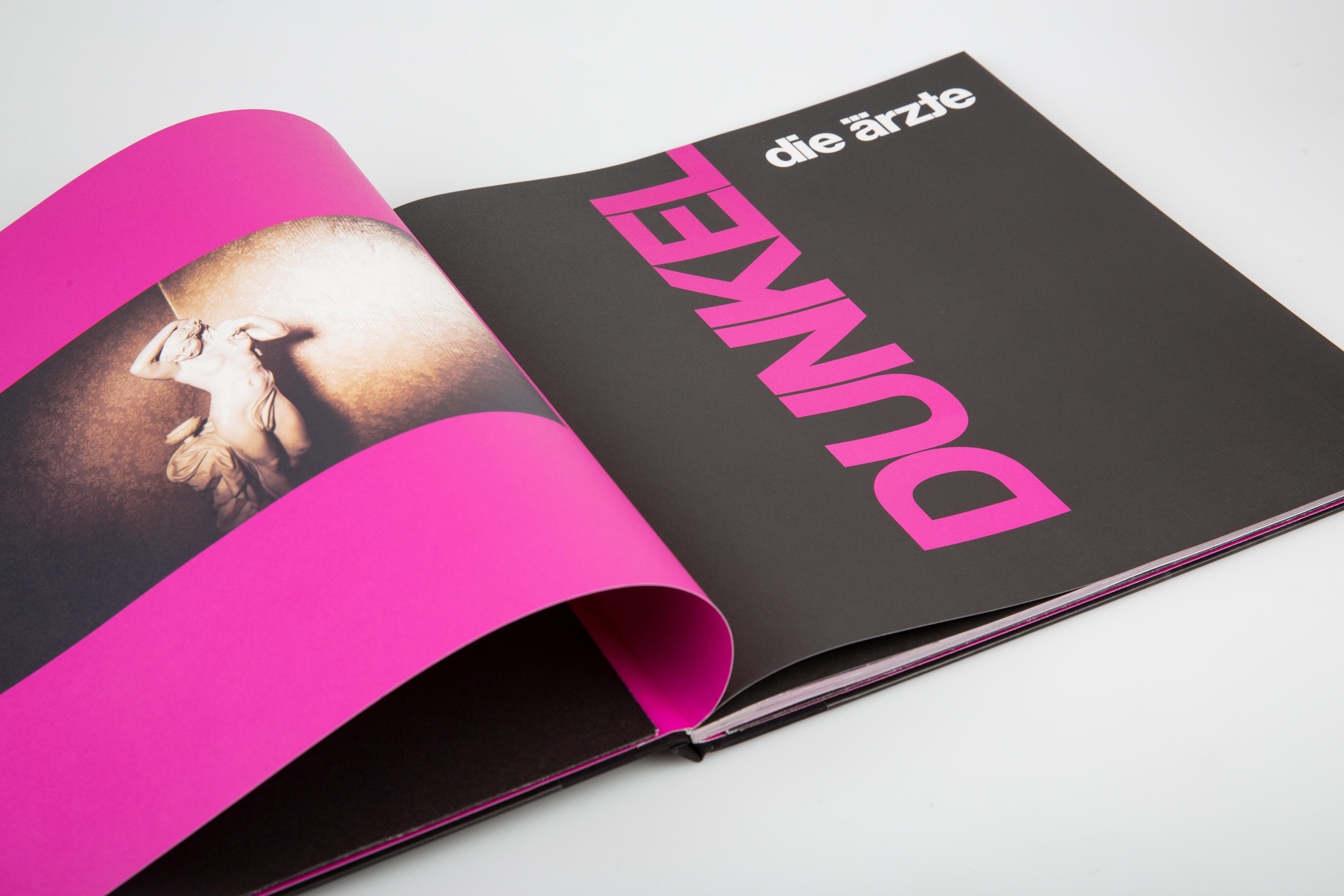 Eine Buchseite mit einer pinkfarbenen Seite und dem Wort 'DUNKEL' in pinkfarbenem Text.