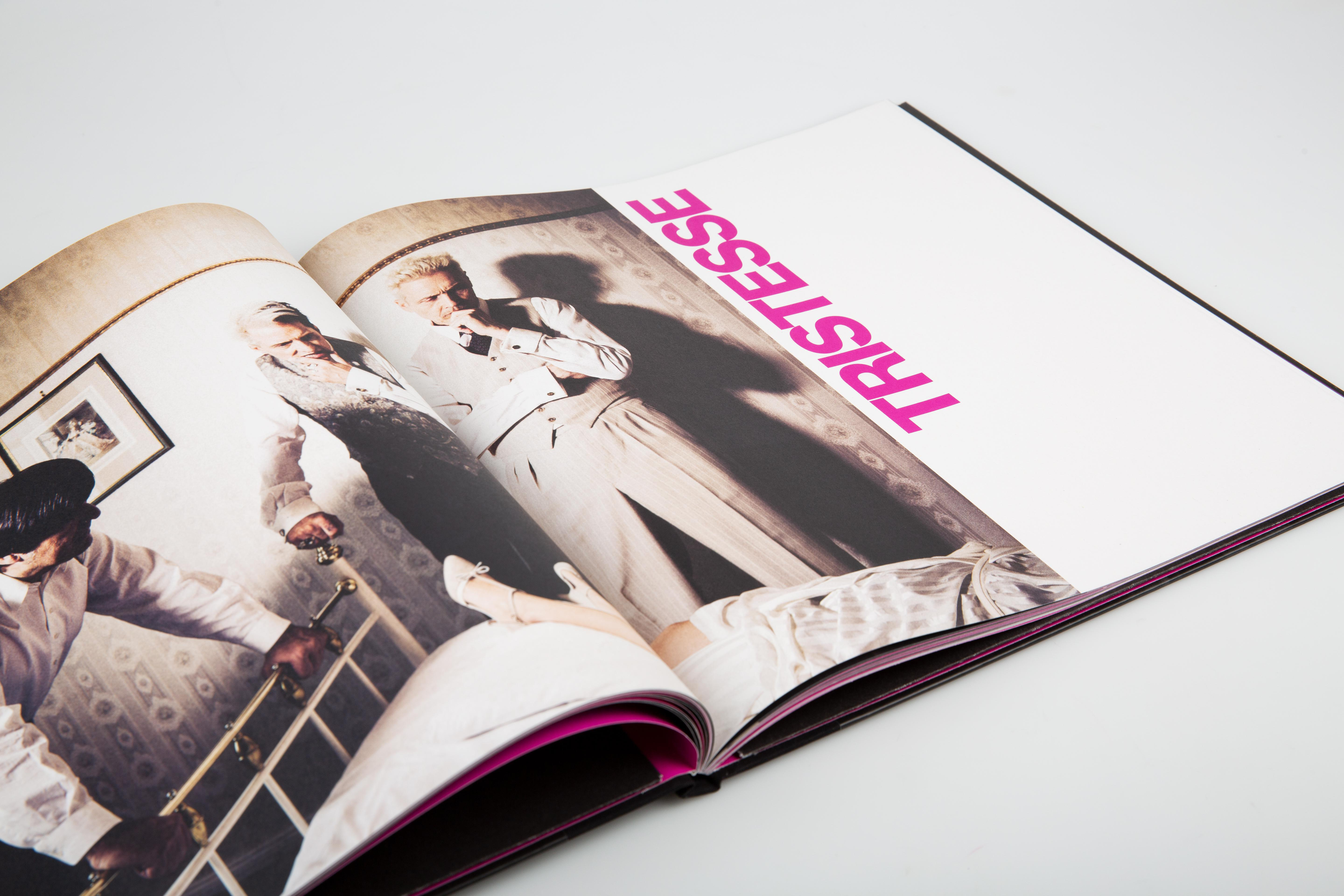 Ein offenes Buch mit einem Bild von Menschen. Das Wort TRISTESSE ist pink.