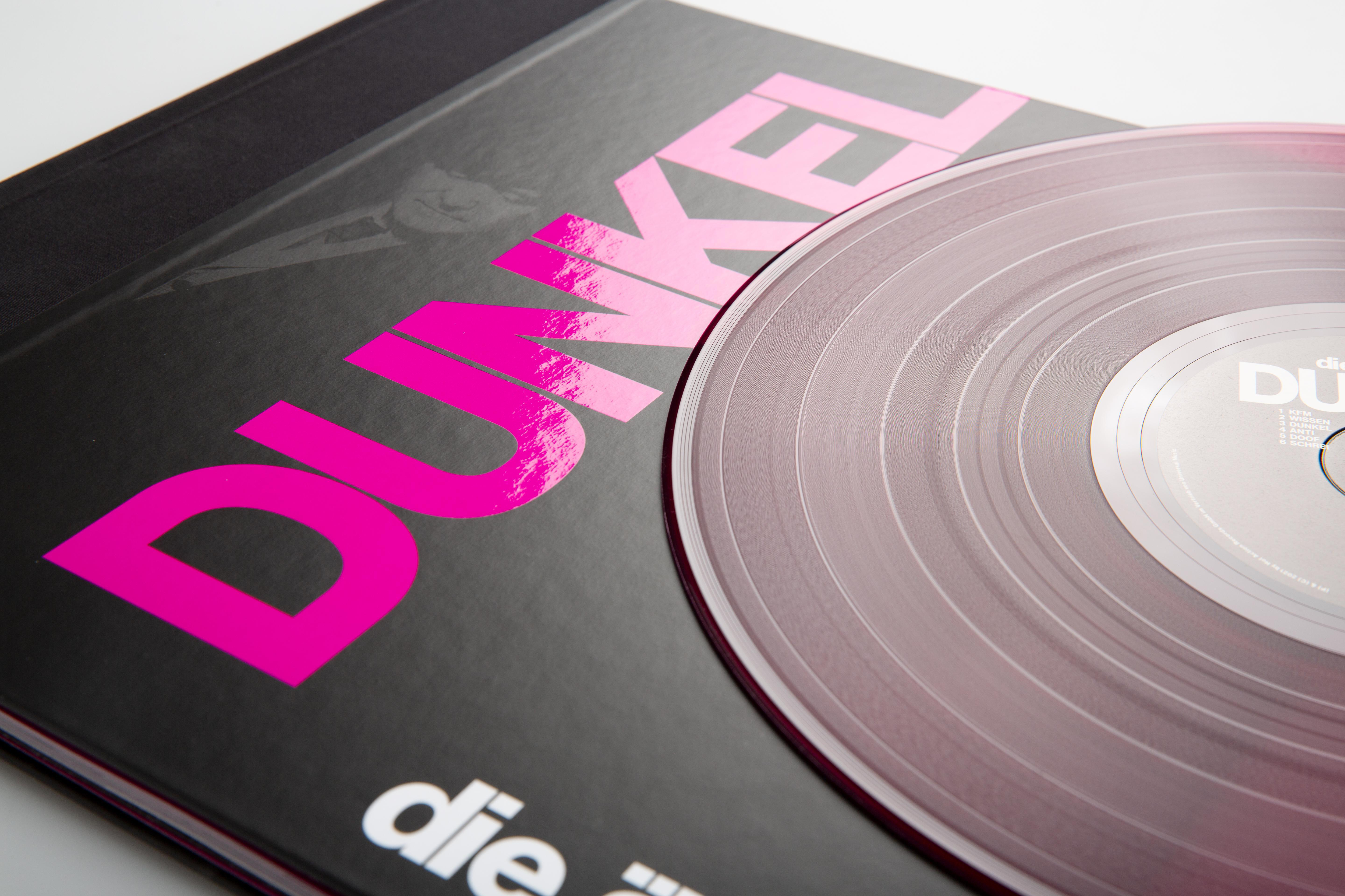 Albumcover mit pinkfarbenem Text und einer transparenten Vinylplatte.