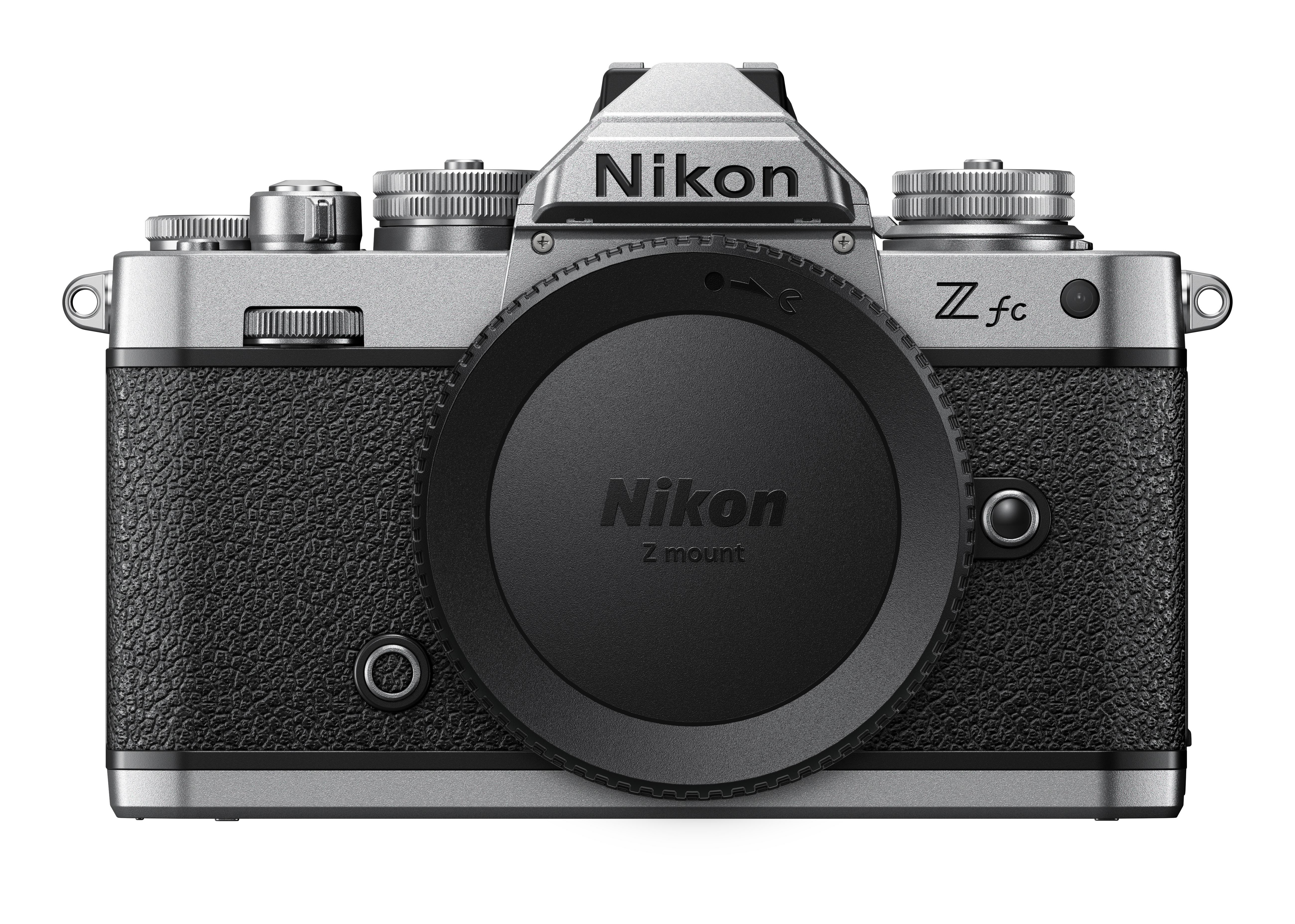 Silberne Nikon Z fc Kamera mit schwarzem Ledergriff, Objektivdeckel und Nikon-Logo auf Weiß.