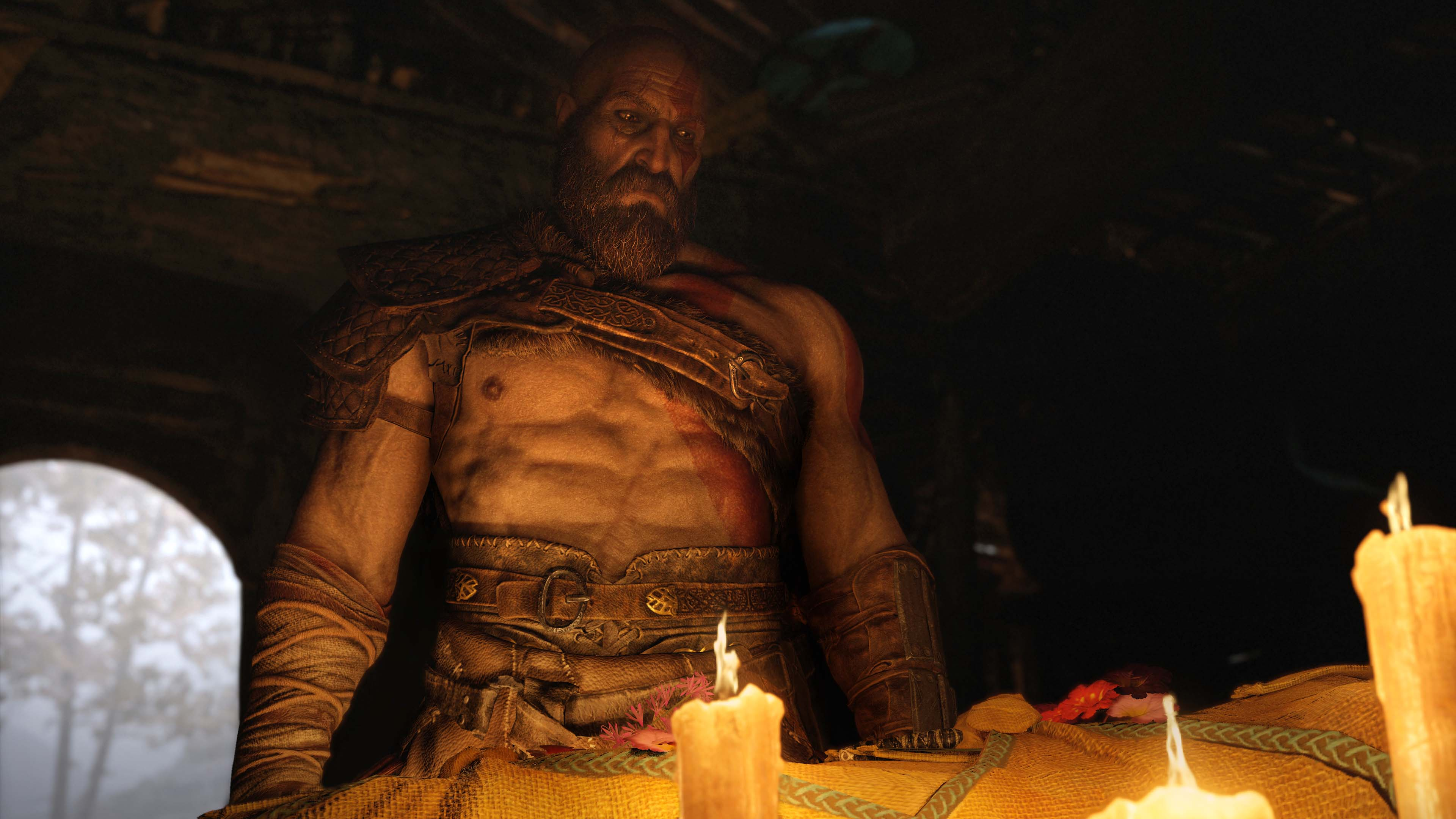 A man with a beard and scars, in a dark room. He is shirtless and has a muscular build.