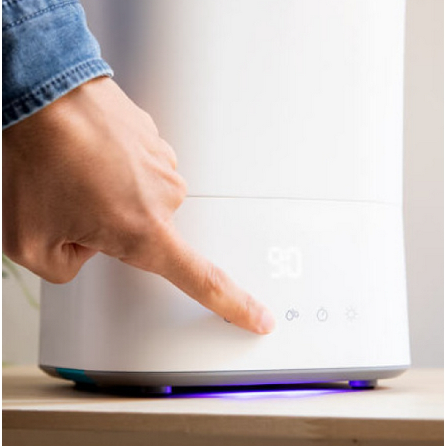 Un dedo presiona un botón en un humidificador blanco con pantalla de 90.