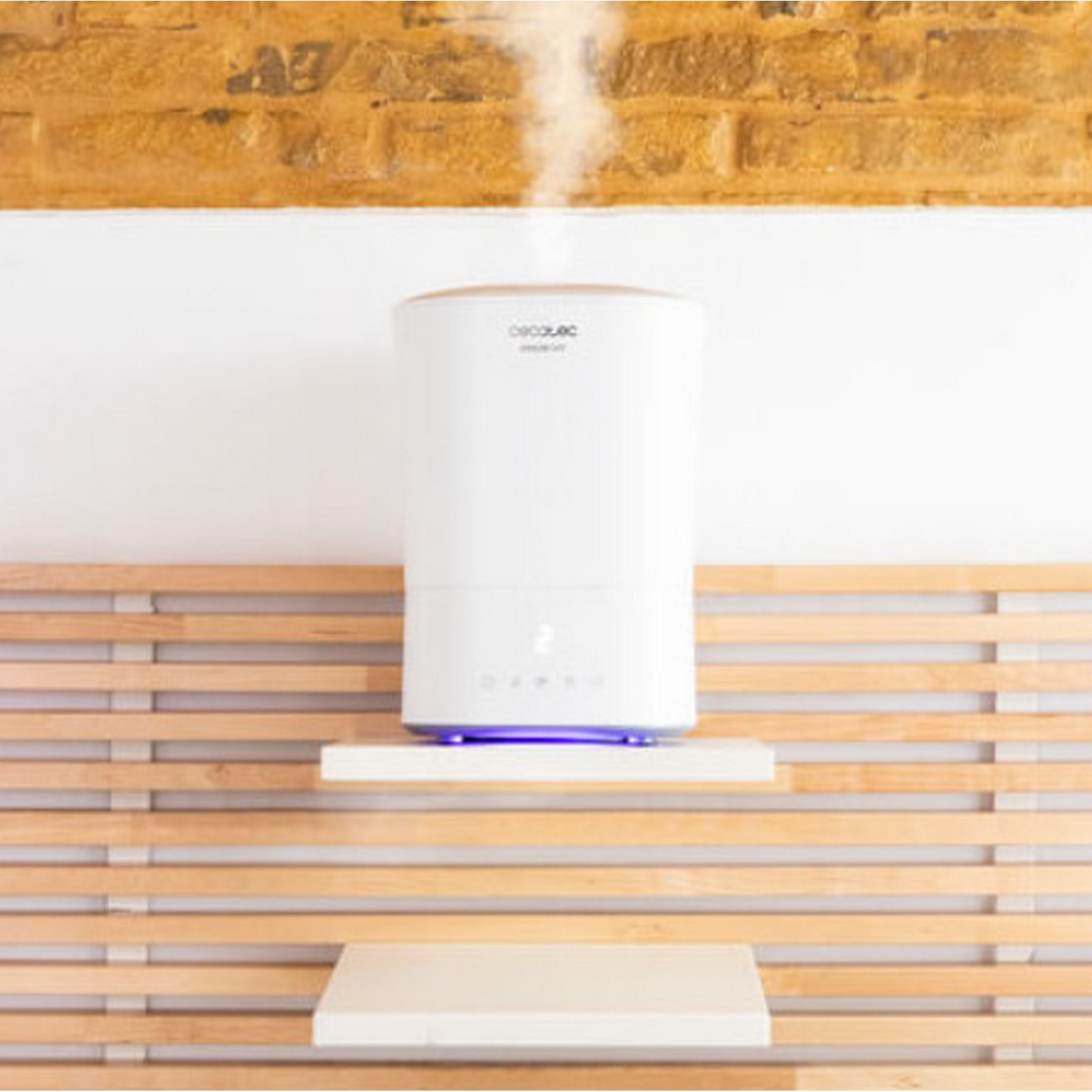 Un humidificador blanco con luz azul sobre un estante contra paredes de listones de madera.