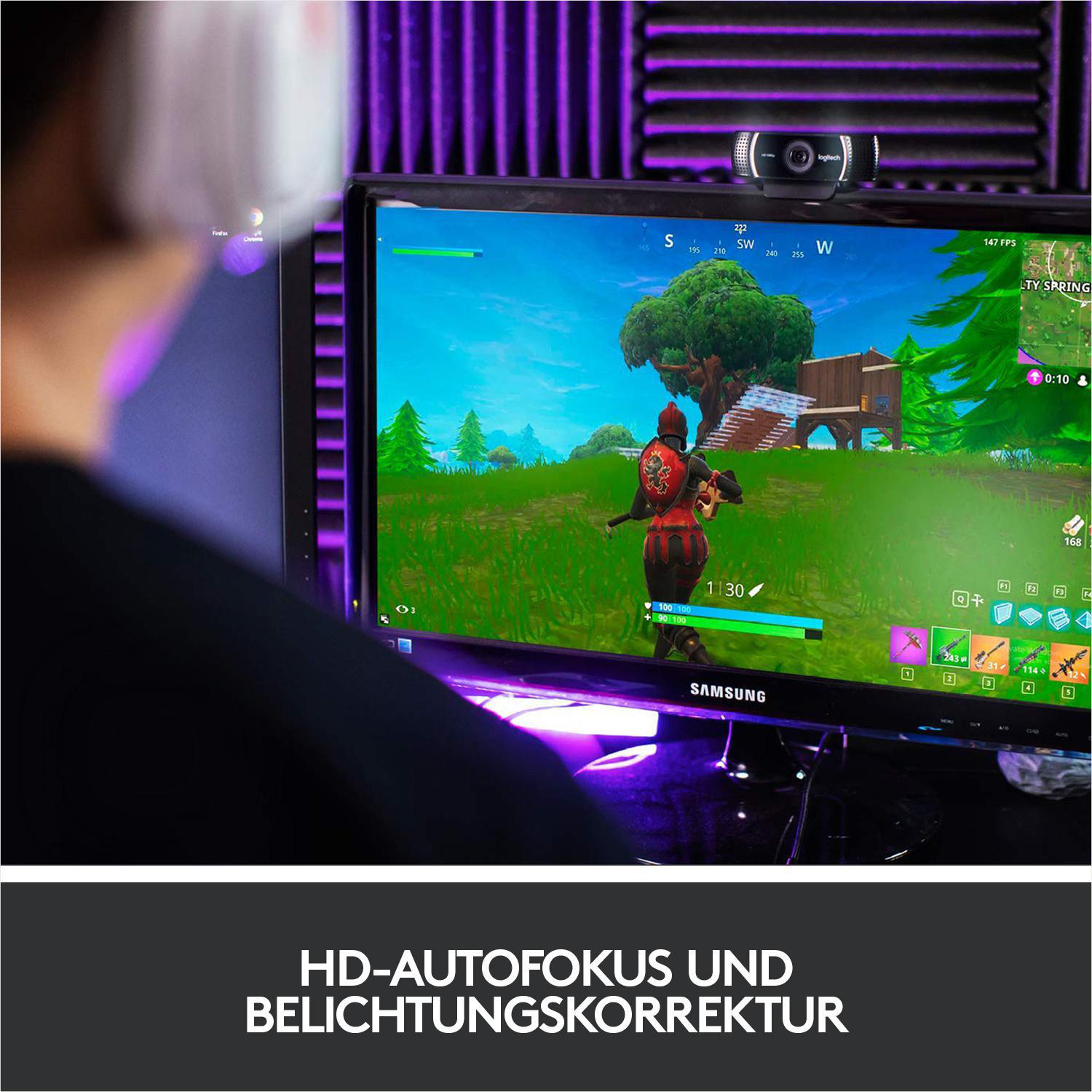 Person spielt Videospiel, Webcam oben auf Monitor, dunkler Raum.