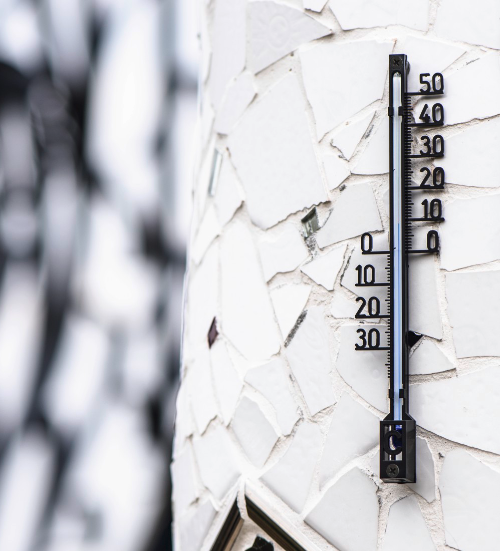 Thermomètre sur un mur carrelé en mosaïque blanche, indiquant la température.