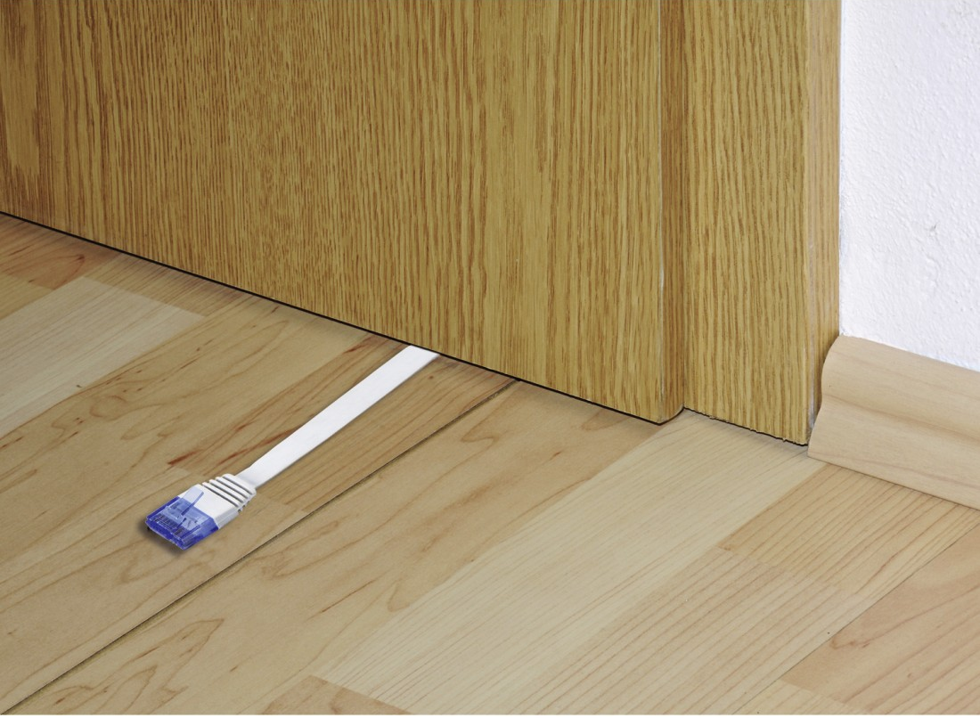 Pavimento in legno con cavo Ethernet che passa sotto la porta. Porta e muro visibili. Connettore blu sul cavo.