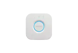 White smart home hub with a blue light, on a white surface. The hub has a Philips logo.