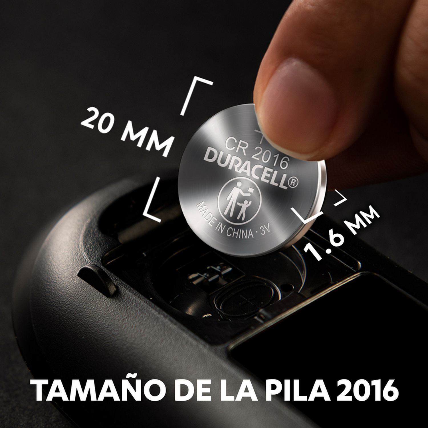 Una pila Duracell CR2016, con medidas en milímetros, sujeta entre los dedos.