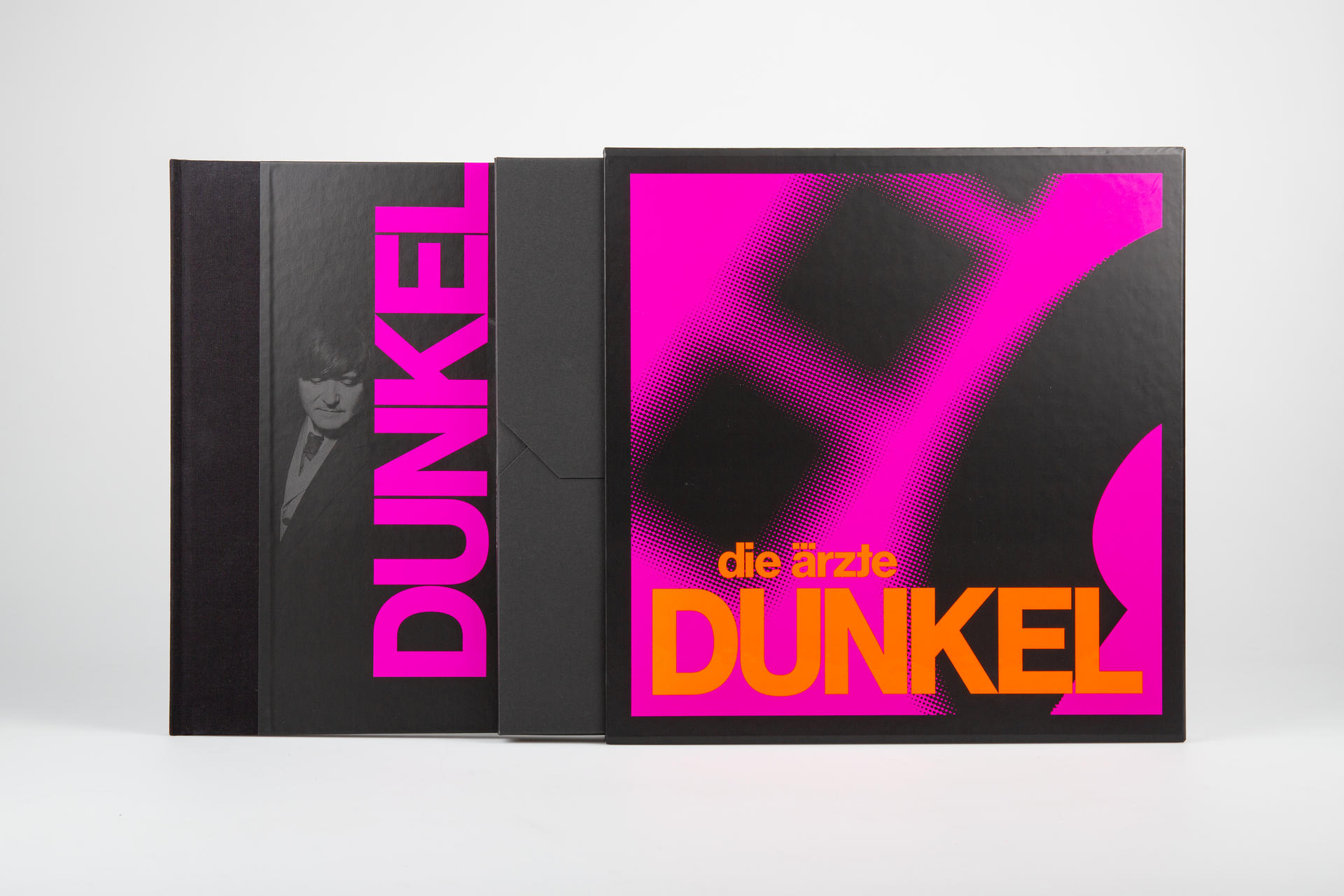 Albumcover mit pinkfarbenem Text 'Dunkel' und einem Bandmitglied-Porträt auf schwarzem Grund.