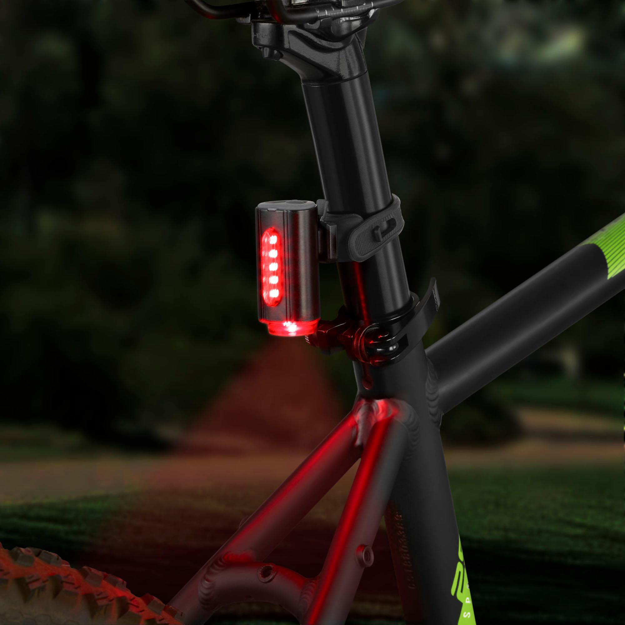 Ein rotes Fahrradlicht ist an einem Fahrrad befestigt. Das Licht ist an. Grüner und schwarzer Fahrradrahmen.