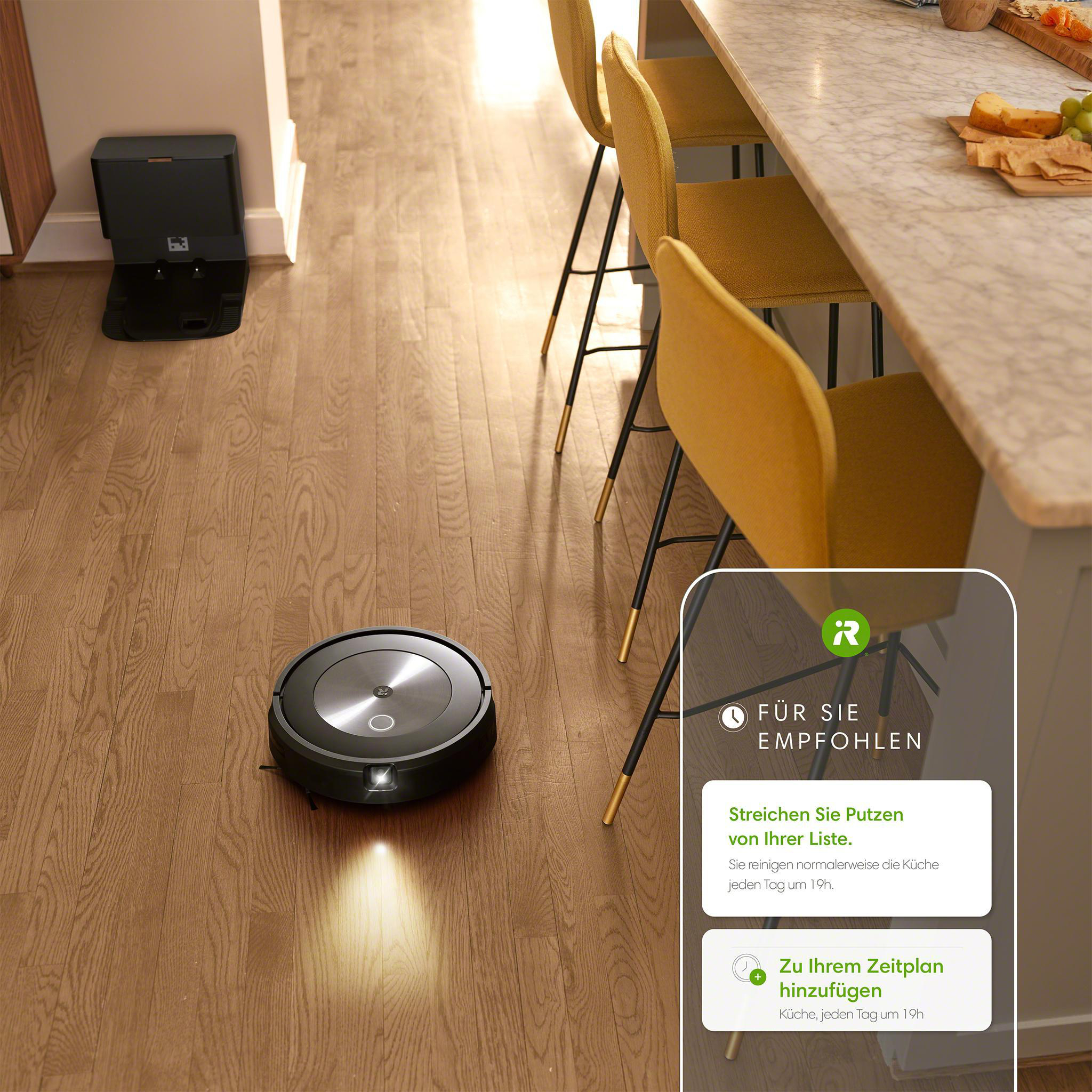 Roboter-Staubsauger auf Holzboden, mit Ladestation und Küche im Hintergrund.