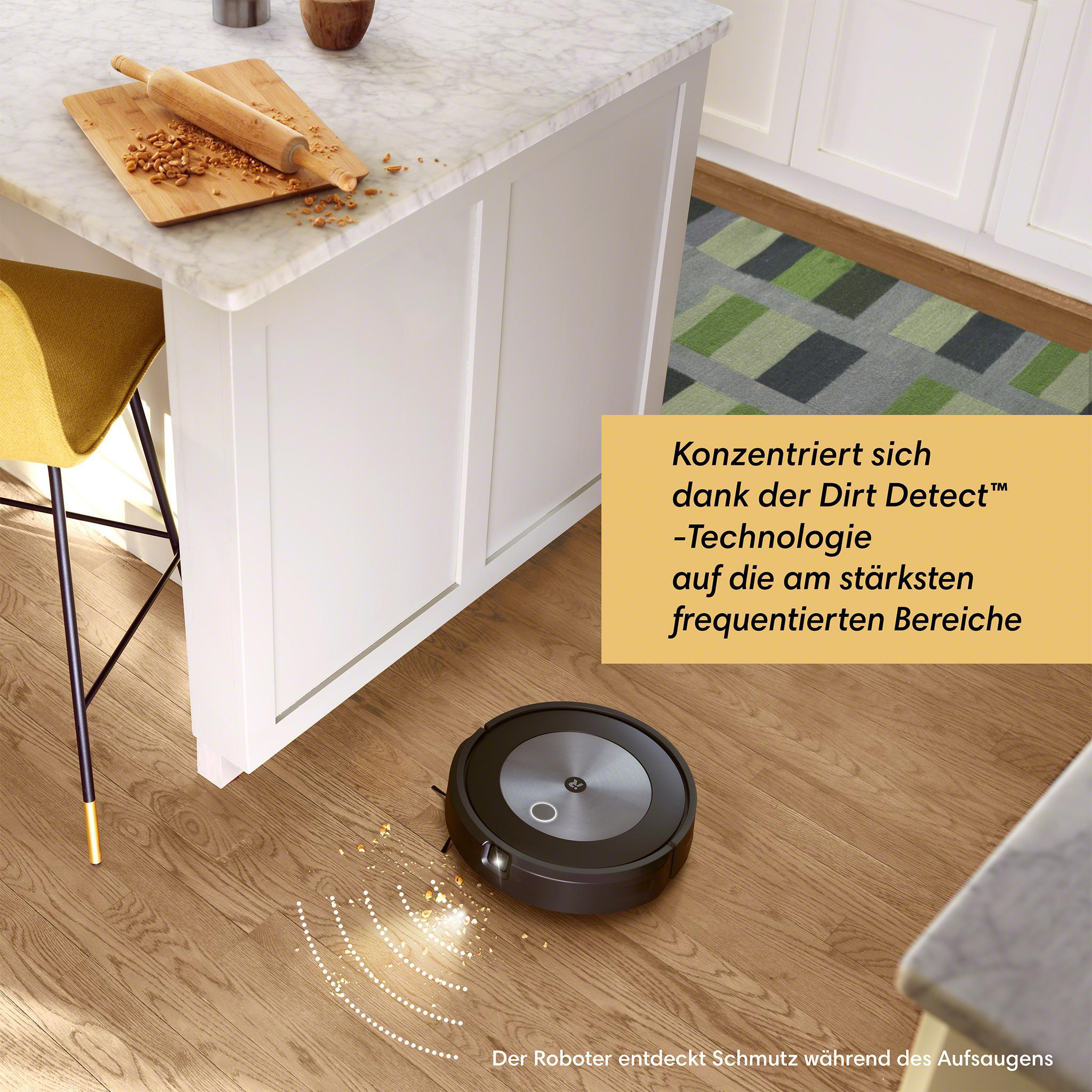 Ein Roboter-Staubsauger auf Holzboden, der Krümel reinigt. Eine Küche mit weißen Schränken.