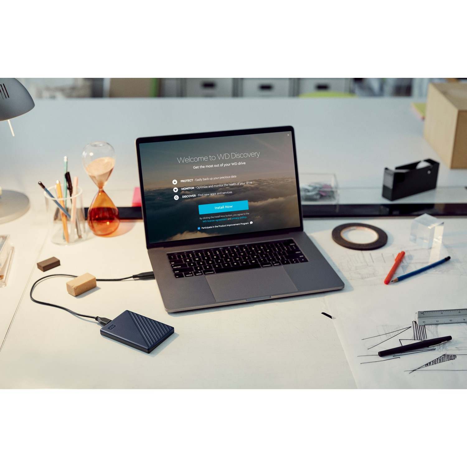 Laptop conectado a un disco duro portátil y otros elementos de escritorio.