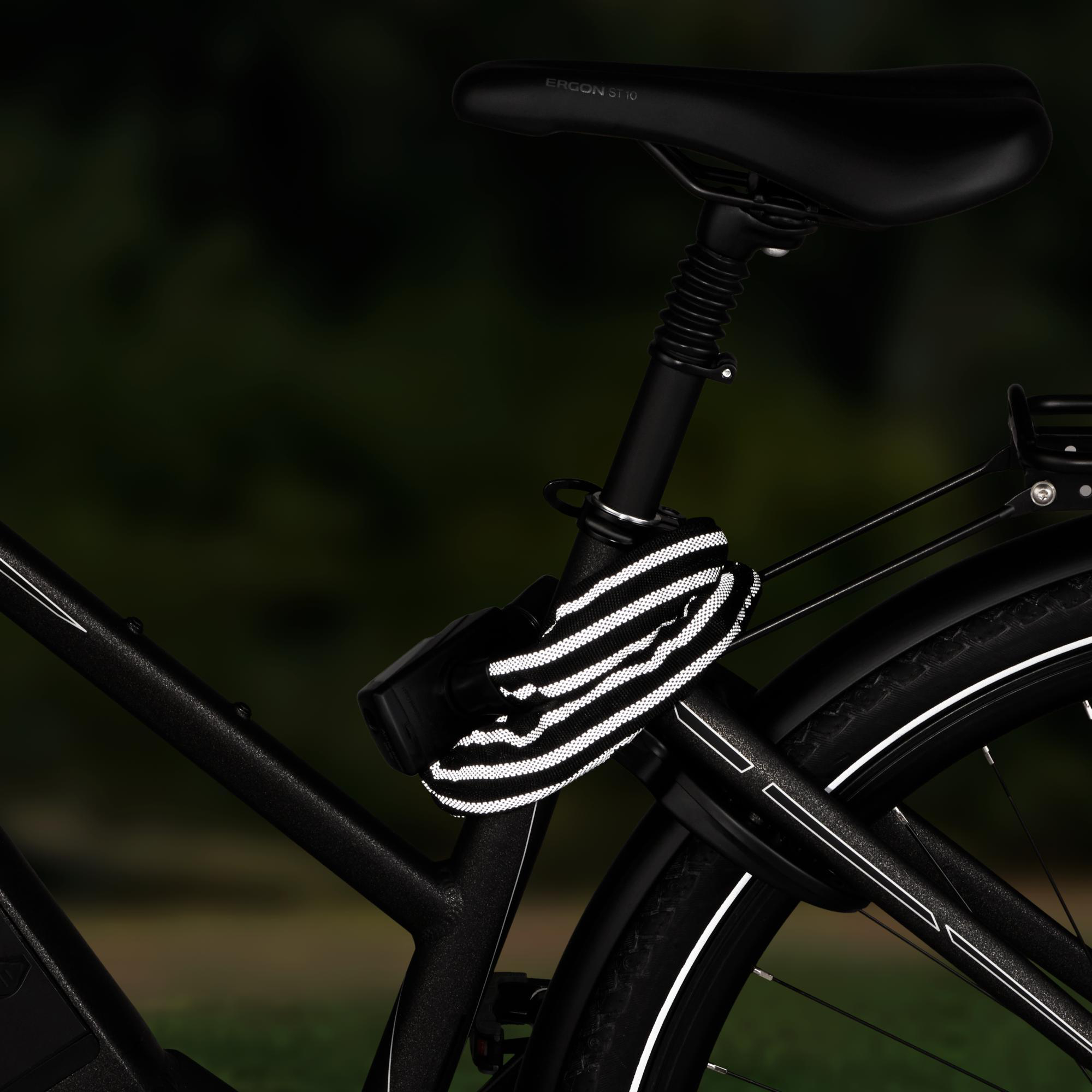 Ein schwarzes Fahrrad mit Kettenschloss vor grünem Hintergrund.