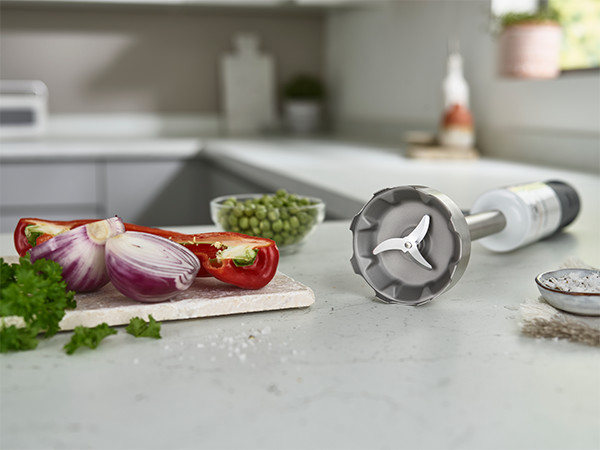 Immersion blender with vegetables on a kitchen counter.