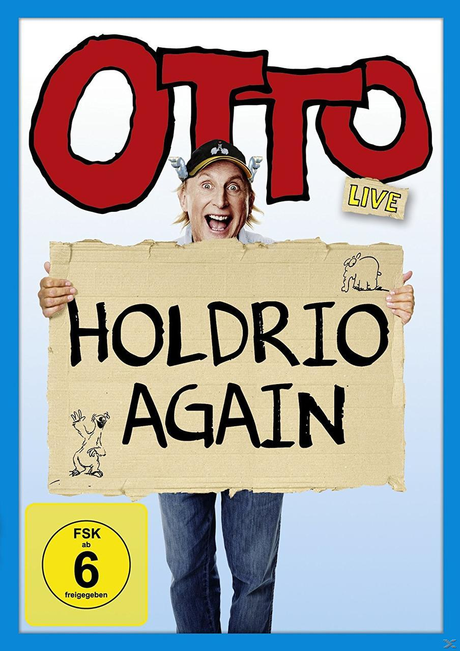 Otto Waalkes hält ein Schild mit der Aufschrift 'HOLDRIO AGAIN'. Er trägt einen Hut und lächelt. Blauer Hintergrund.