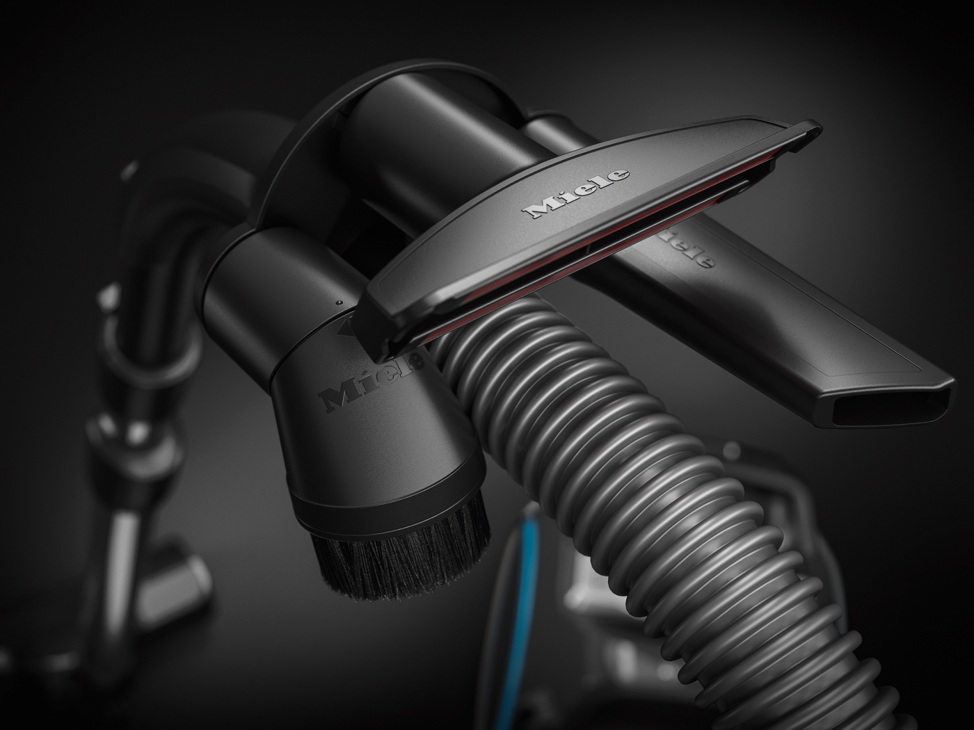 Black vacuum cleaner attachments with 'Miele' brand, a hose, and a brush.