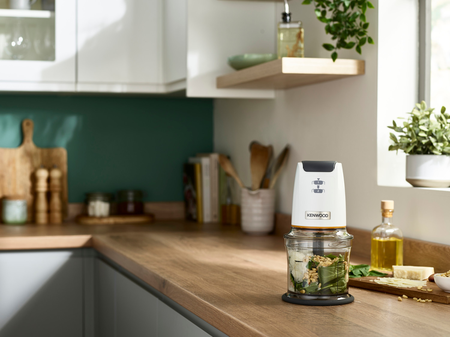 Küchentheke mit Küchenmaschine, Zutaten und einer kleinen Pflanze.
