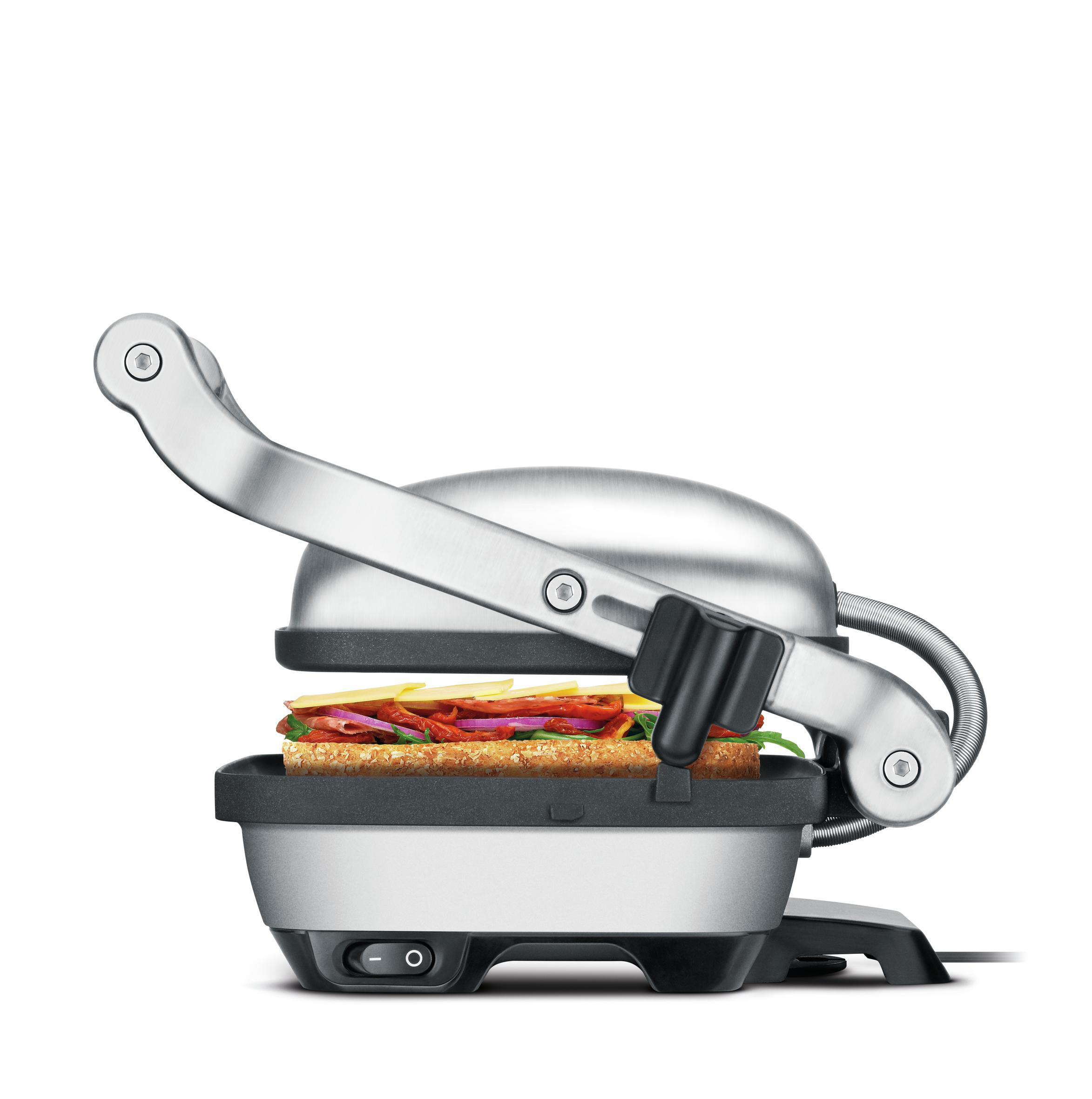Eine Sandwichpresse mit einem Sandwich darin. Edelstahl mit schwarzem Griff. Weißer Hintergrund.