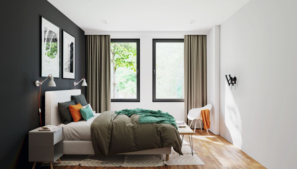 Bedroom interior with a bed, art, windows, curtains, and a side table.