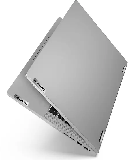 Un portátil plateado está abierto. El logotipo de Lenovo es visible en la tapa. El portátil está sobre una superficie blanca.