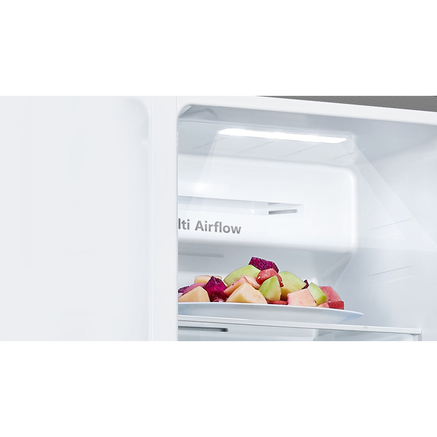Interior de un refrigerador blanco con un plato de frutas mixtas.
