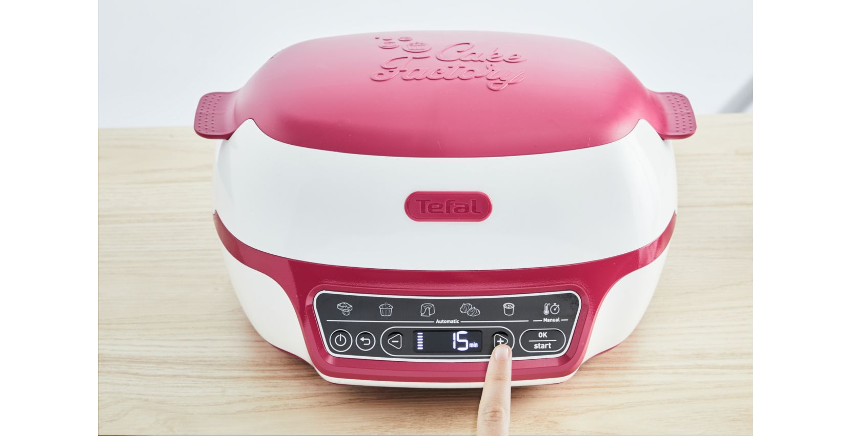 Rood en wit Tefal Cake Factory-apparaat. Een vinger wijst naar het display van de timer, dat '15 min' aangeeft.