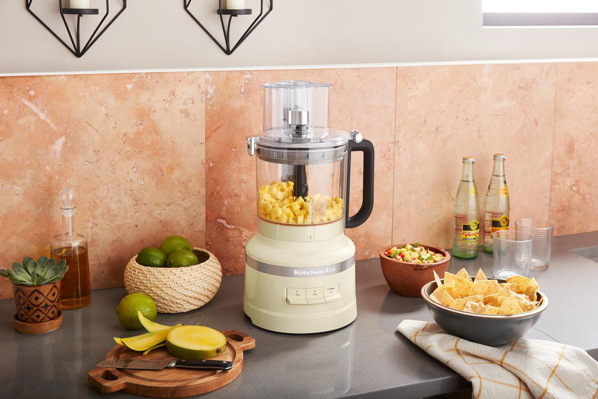 KitchenAid-Küchenmaschine mit Mangos und Limetten auf einer Arbeitsplatte.