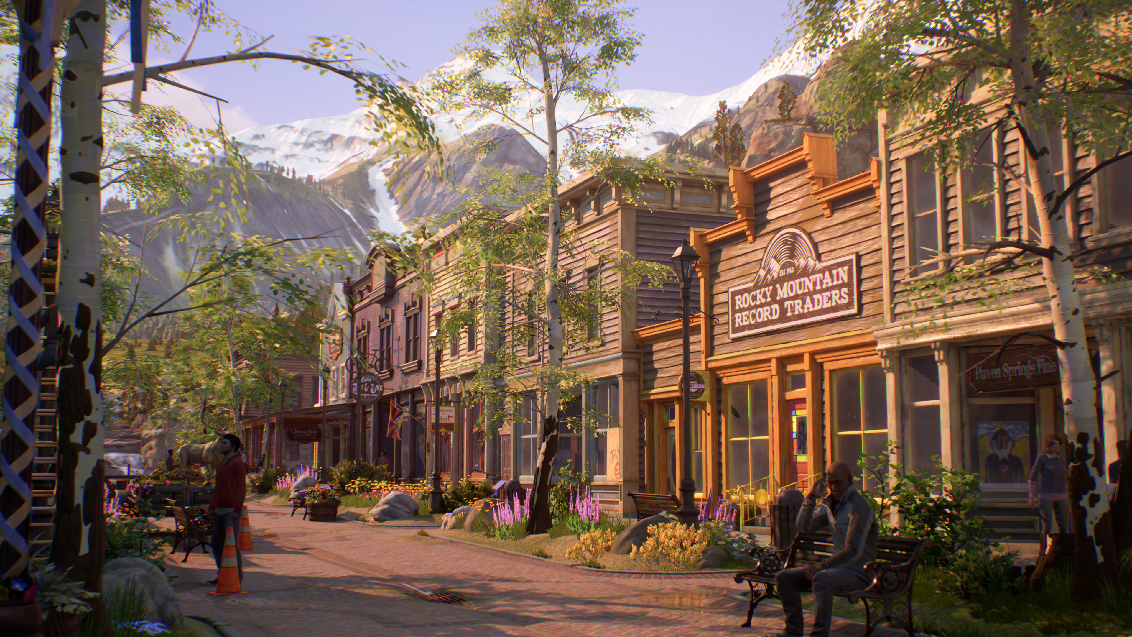 Rue d'une ville de l'Ouest avec des magasins, des arbres et des montagnes en arrière-plan.