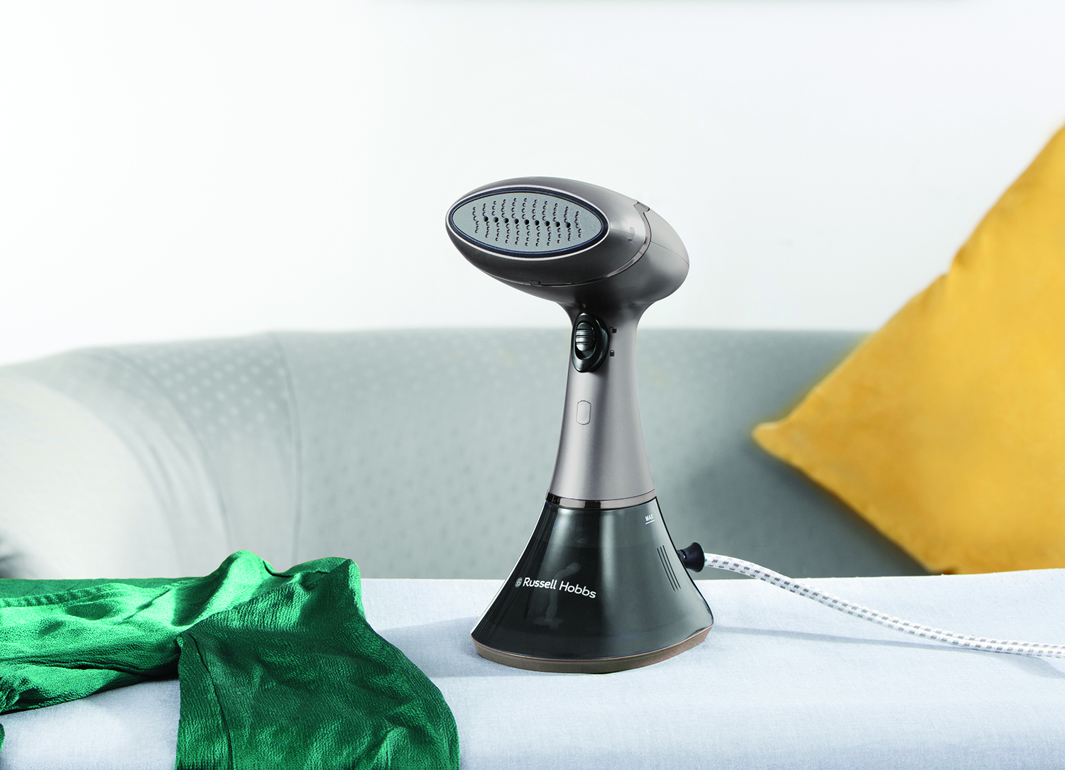 Een Russell Hobbs kledingstomer op een bank met een groen kledingstuk.