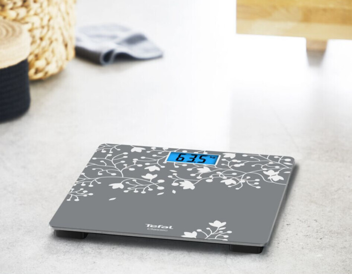 Digitális mérleg virágmintával, 63,5 kg-os súlyt mutat.