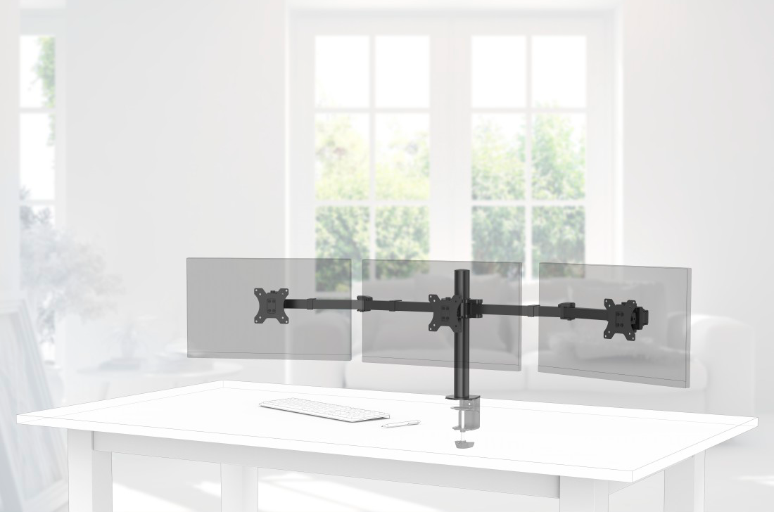 Support triple moniteur sur un bureau blanc. L'arrière-plan est une pièce floue avec un canapé et une fenêtre.