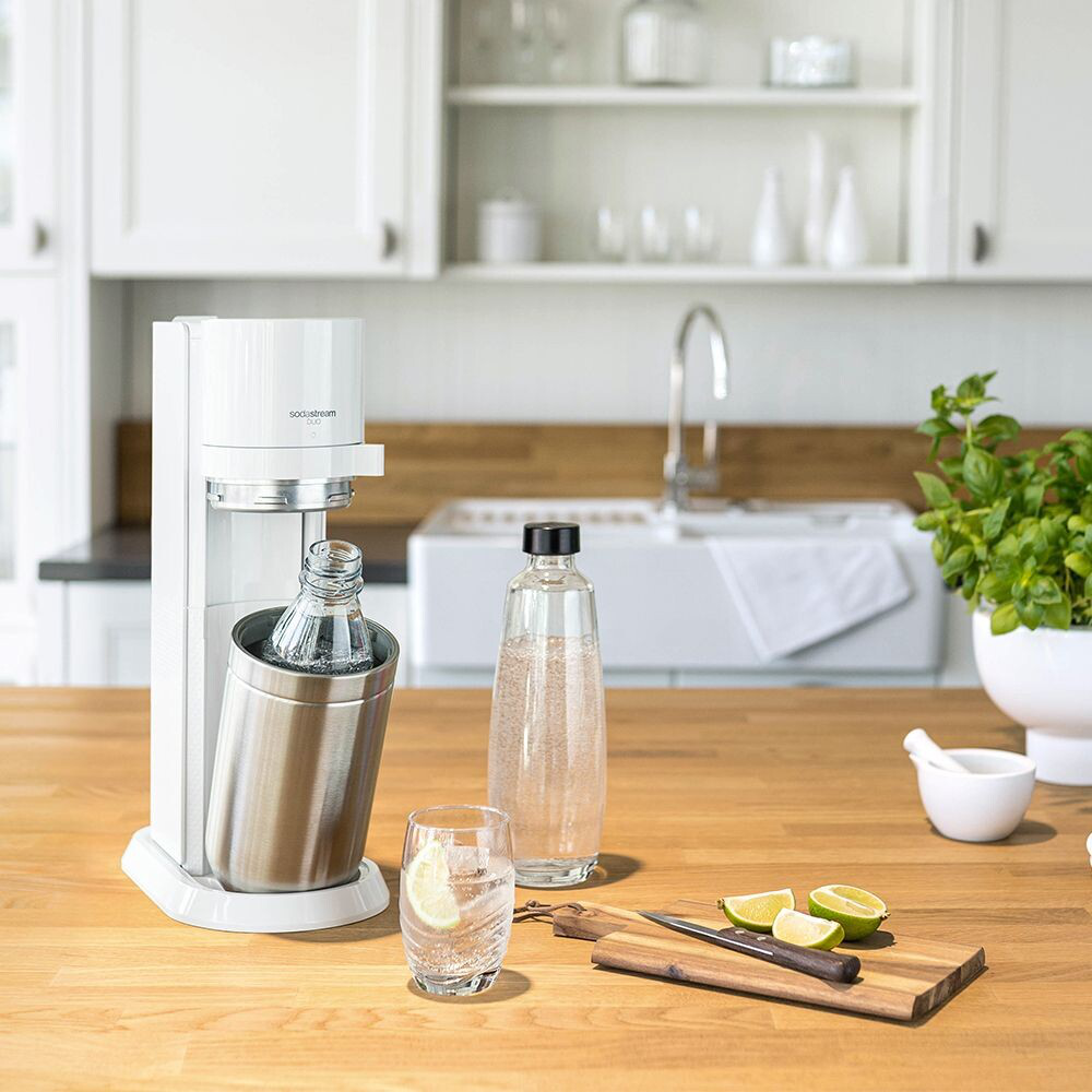 Eine Soda Stream Maschine mit einem Glas und einer Zitronenscheibe auf dem Tisch.