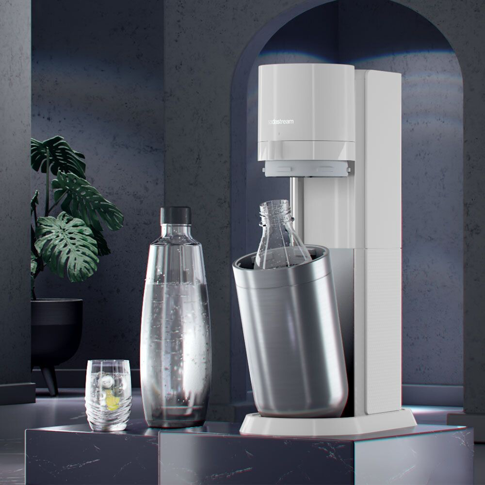 Weiße SodaStream-Maschine mit einer Flasche darin, eine weitere daneben und ein Glas mit Zitrone.