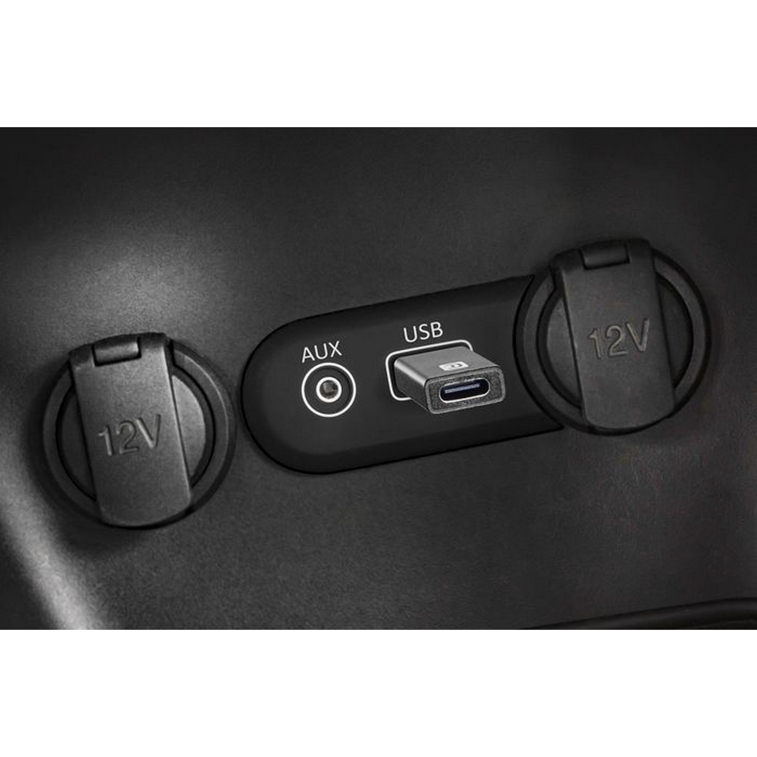 Consola de coche con puertos USB, AUX y 12V. El puerto USB tiene un adaptador USB-C conectado.