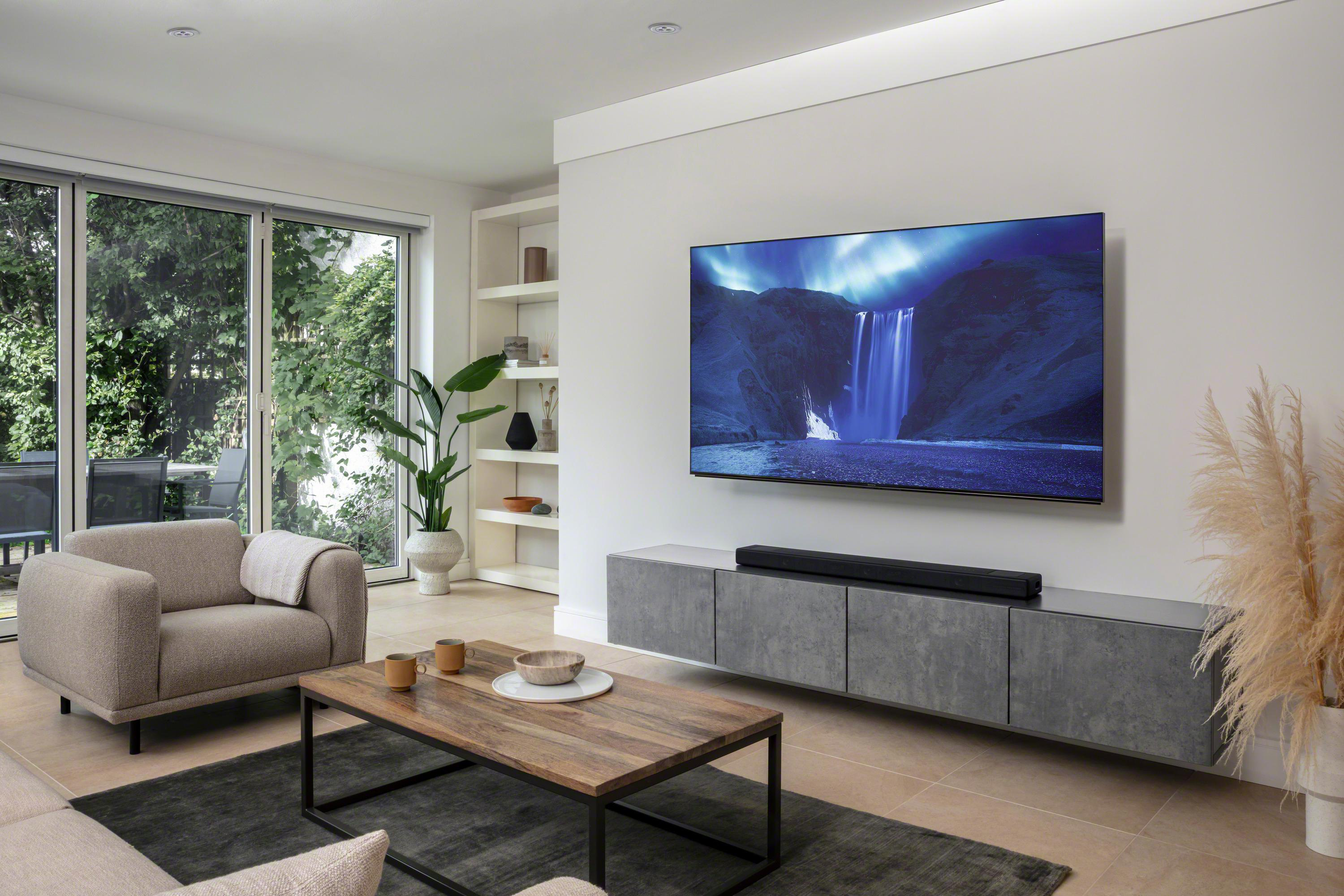 Wohnzimmer mit Fernsehbildschirm, Sofa, Tisch und Teppich.
