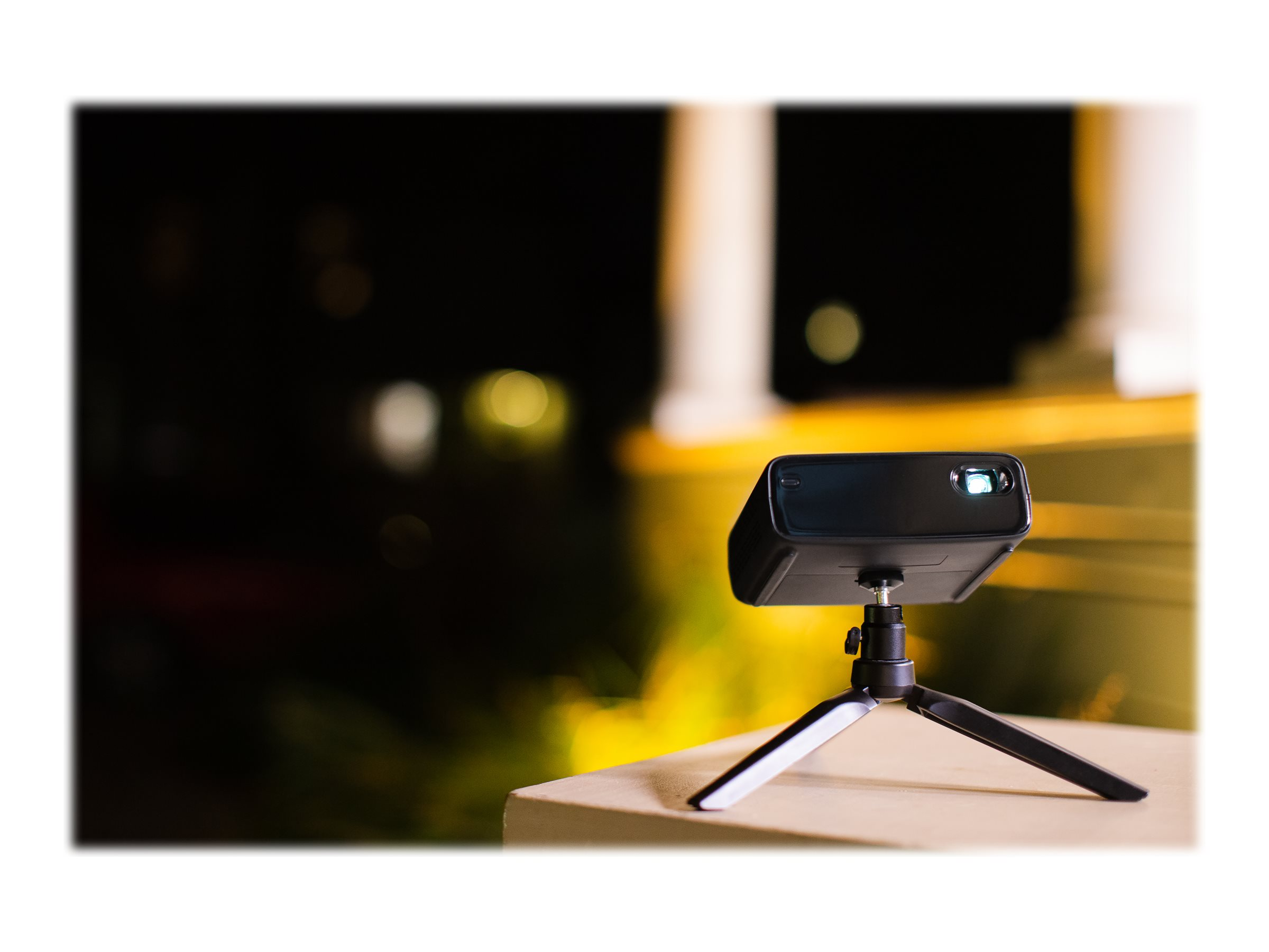 Zwarte projector op een statief, die een licht op de muur projecteert. De achtergrond is donker en wazig.