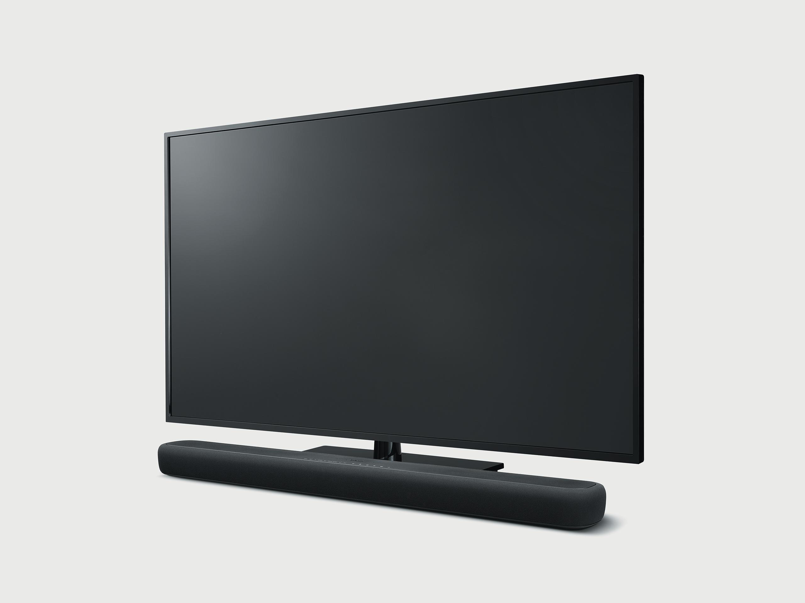 Schwarzer Fernseher mit Soundbar darunter. Grauer Hintergrund.